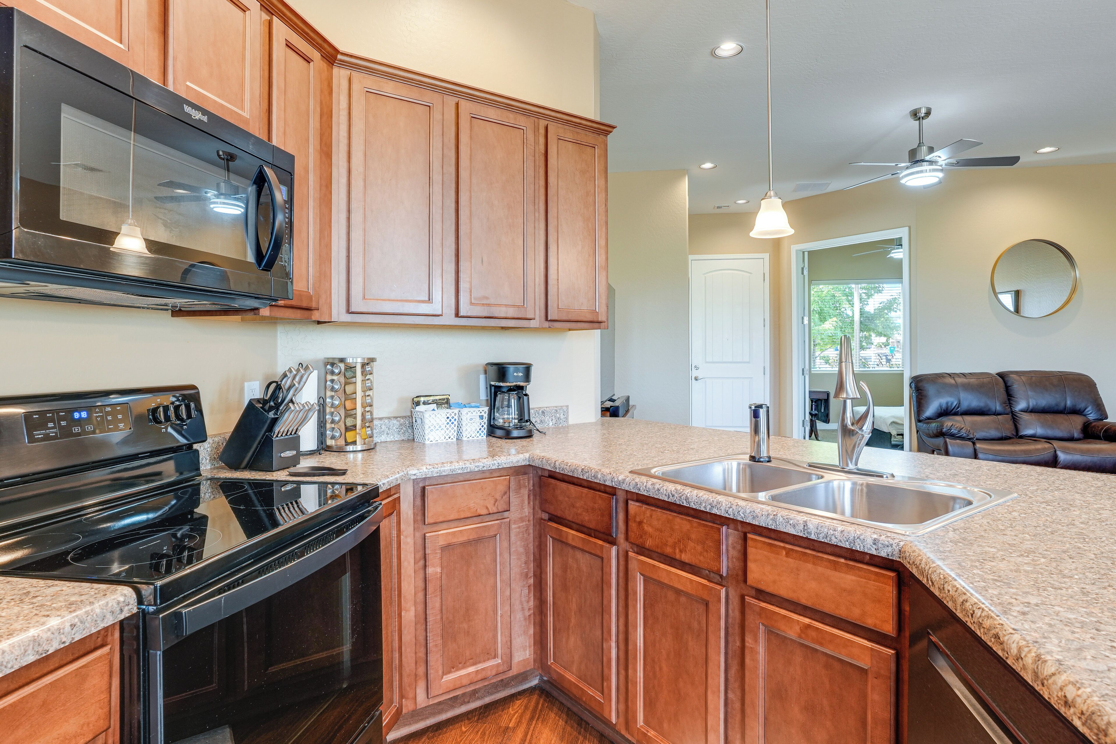 A kitchen with wooden cabinets, a black stove, a microwave, and a granite countertop.