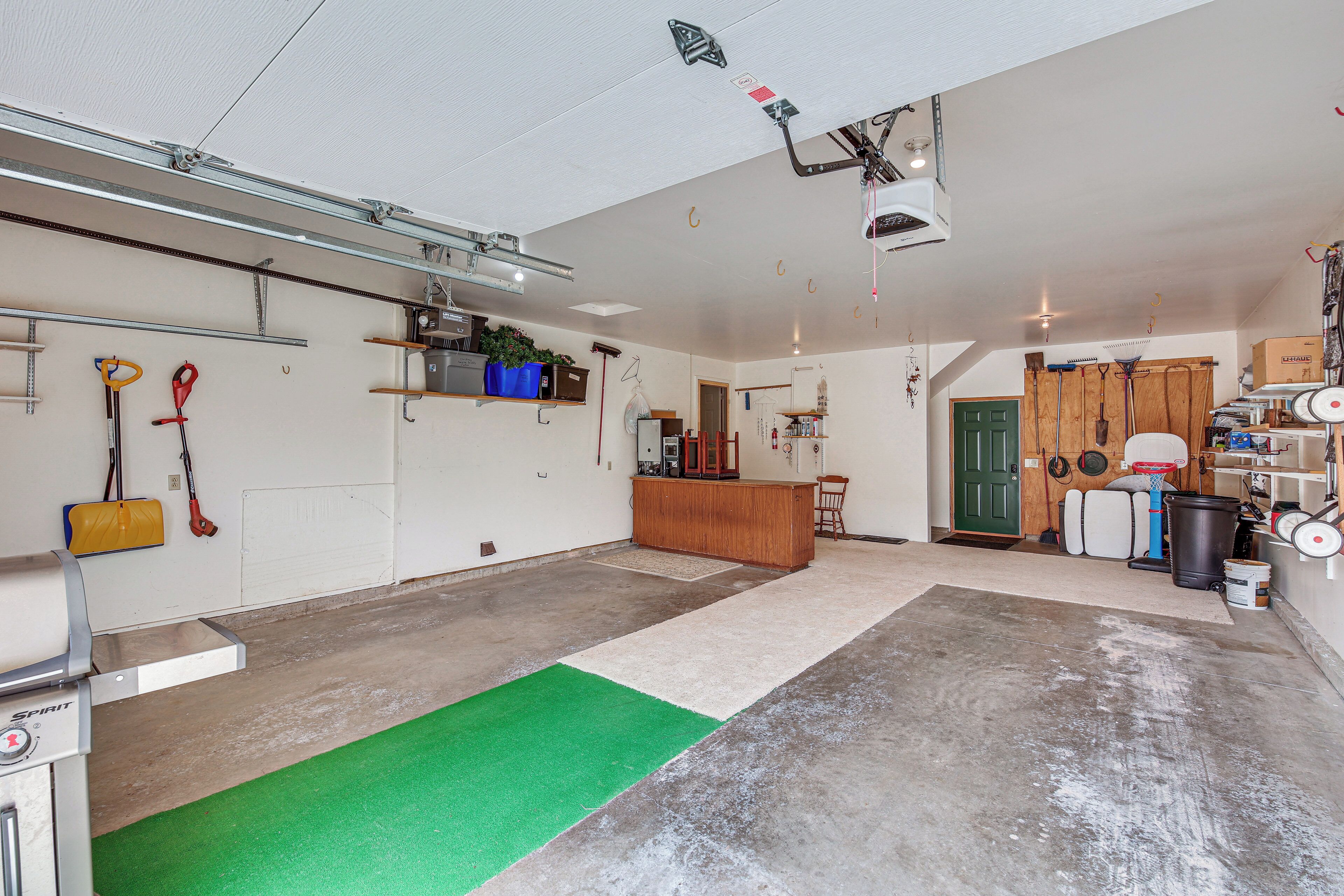 Een ruime garage met een betonnen vloer, een groen vloerkleed en diverse gereedschappen en apparatuur.