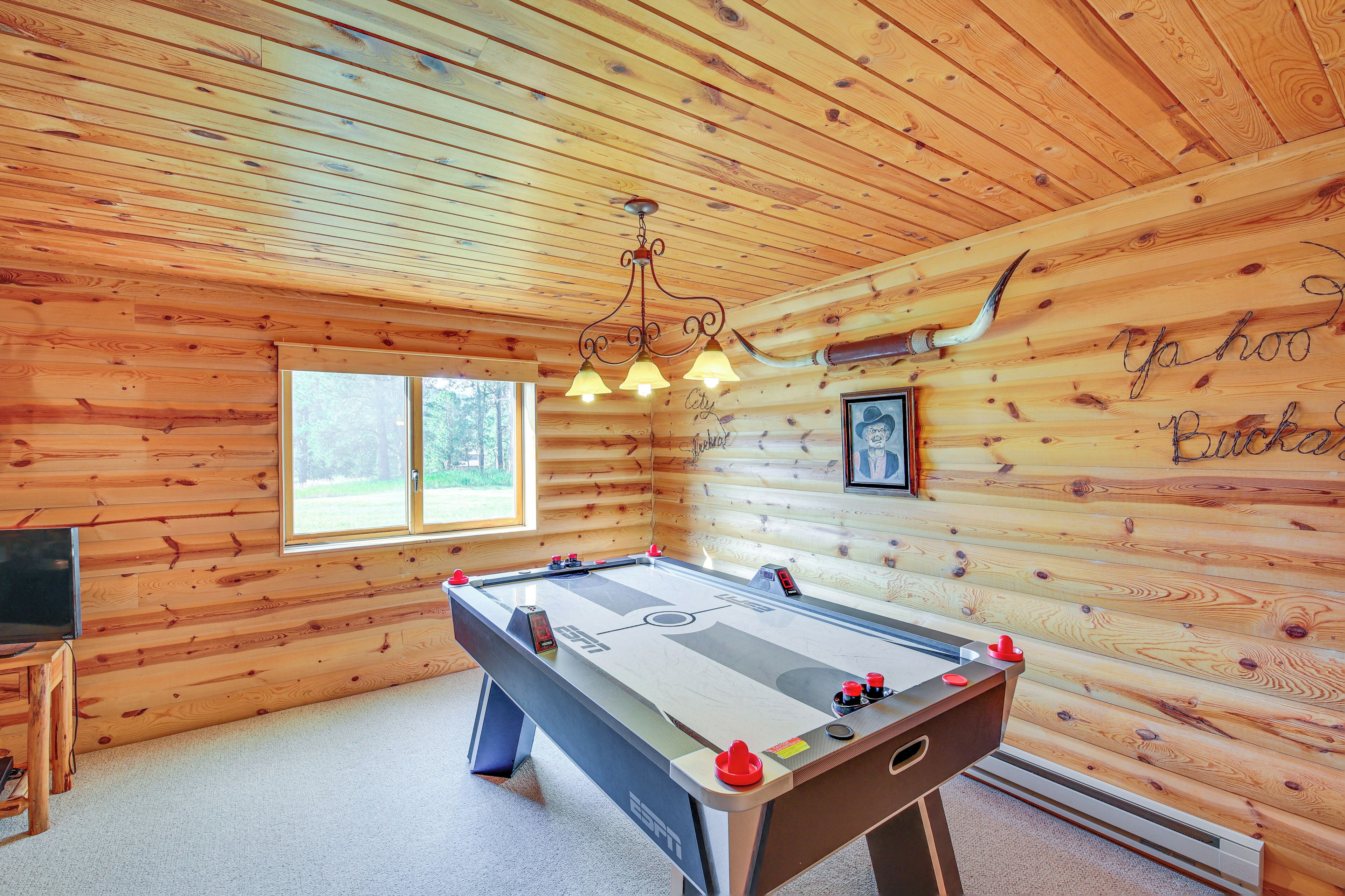 A wooden room with a pool table, a television, and a window.