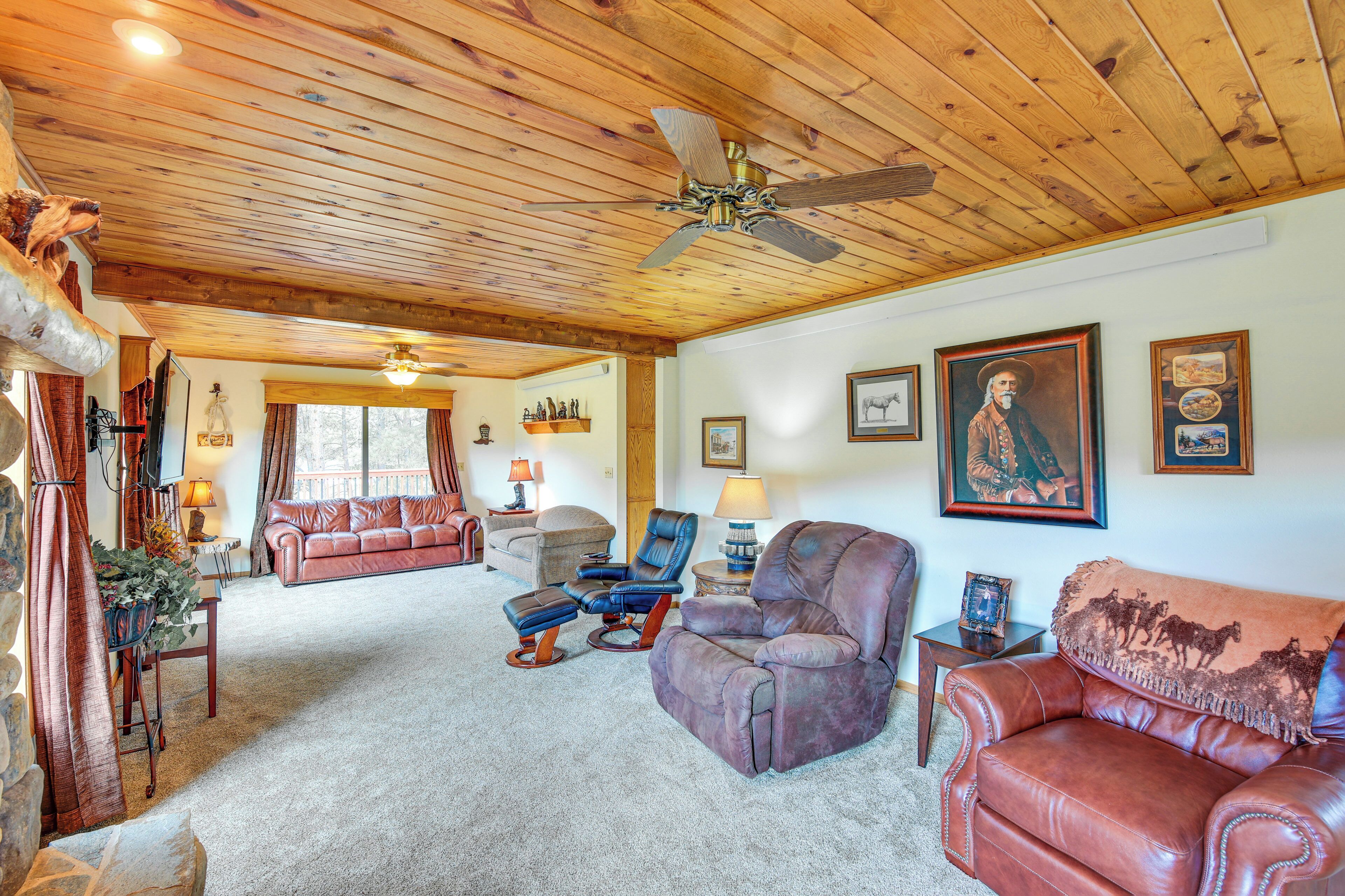 A spacious living room with a high ceiling, leather sofas, a fireplace, and a large window.