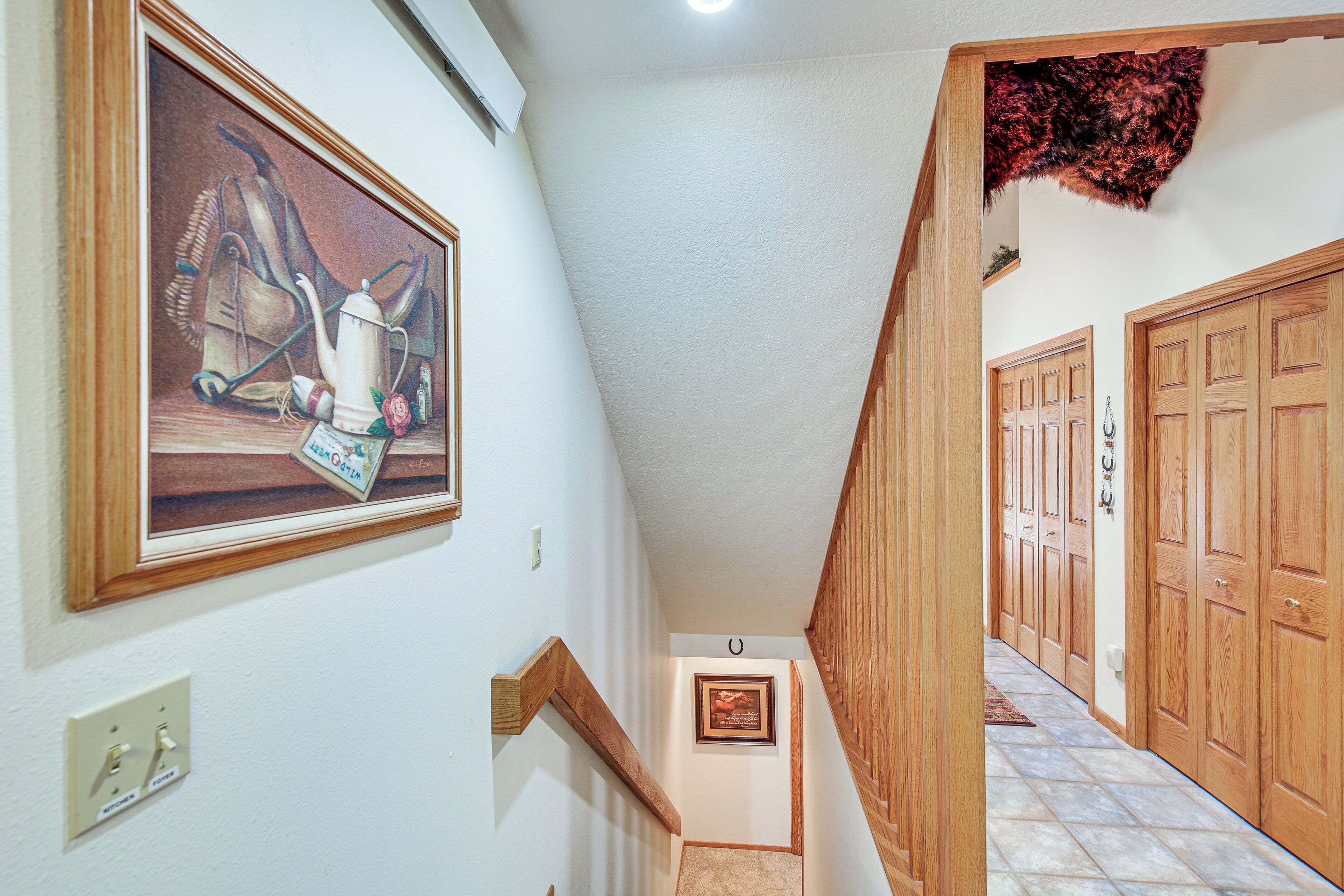 Eine Treppe mit einer Holzhandläufe, ein gerahmtes Bild an der Wand und eine Tür am Fußende.