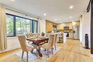 Een moderne keuken met houten kastjes, roestvrijstalen apparatuur en een eethoek met een grote tafel en stoelen.