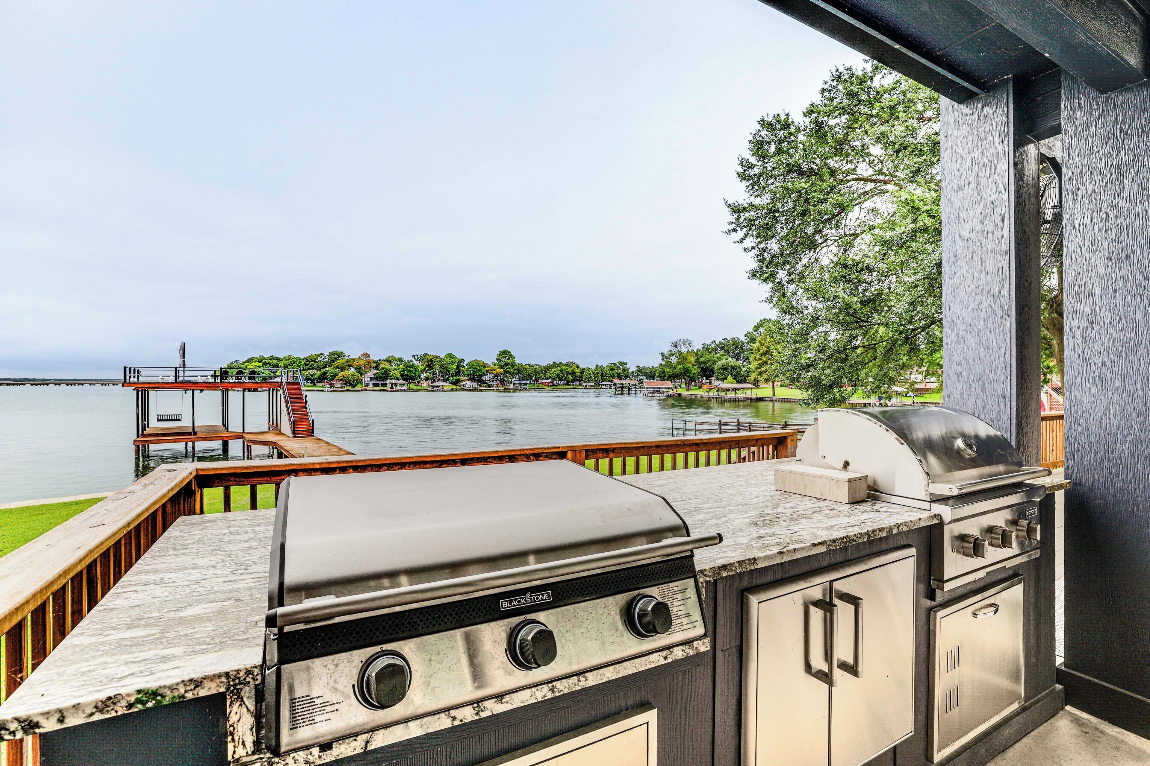 An outdoor grill area with a view of a lake and dock.