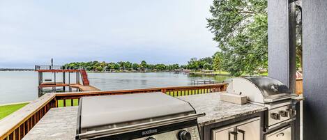 An outdoor grill area with a view of a lake and dock.