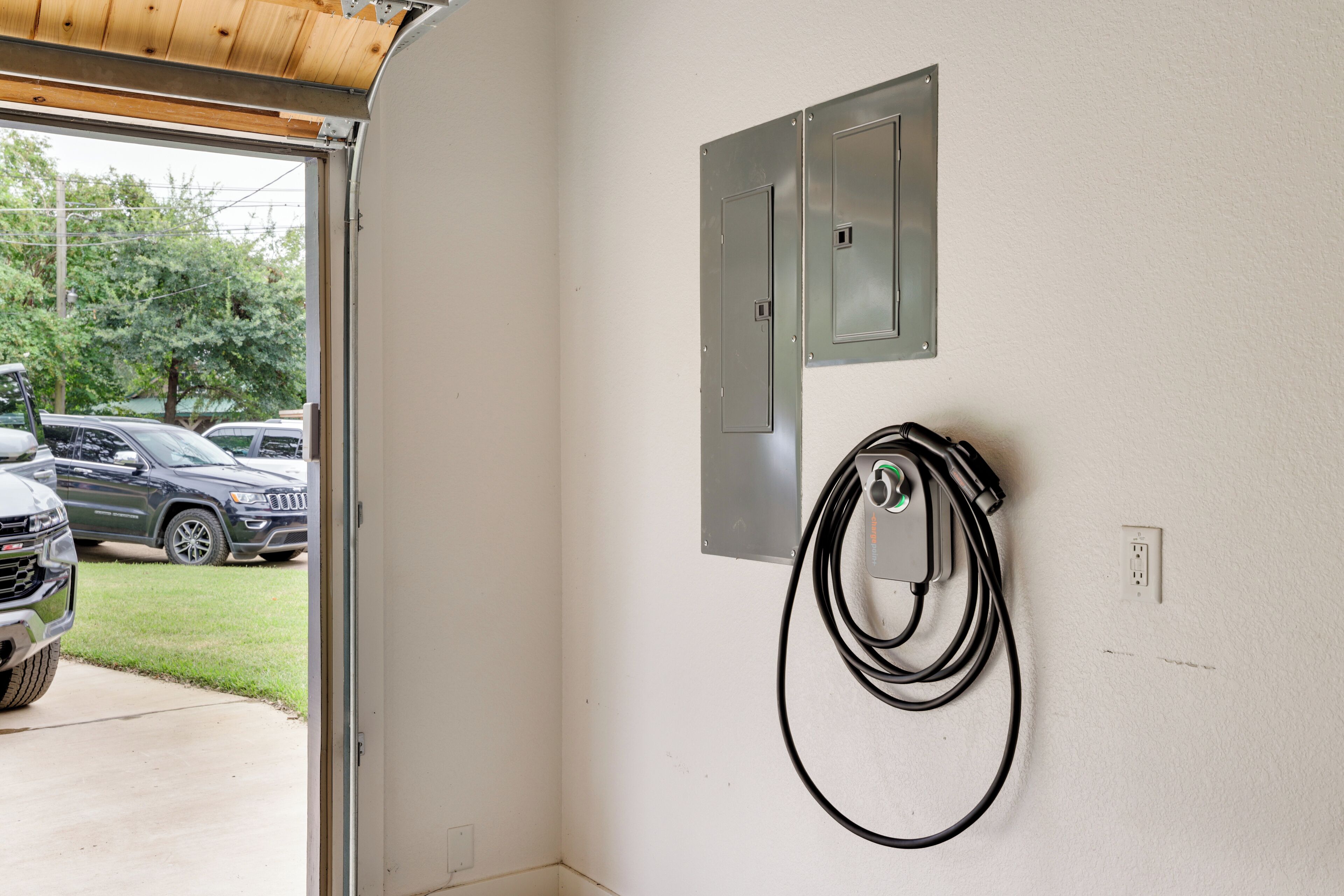 Una estación de carga para vehículos eléctricos, con un cable conectado a un enchufe de pared.