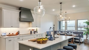 A modern kitchen with a large island, pendant lights, and a view of the water. - Hot Tub, Fire Pit! High-end Cedar Creek Lake Haven (Mabank)
