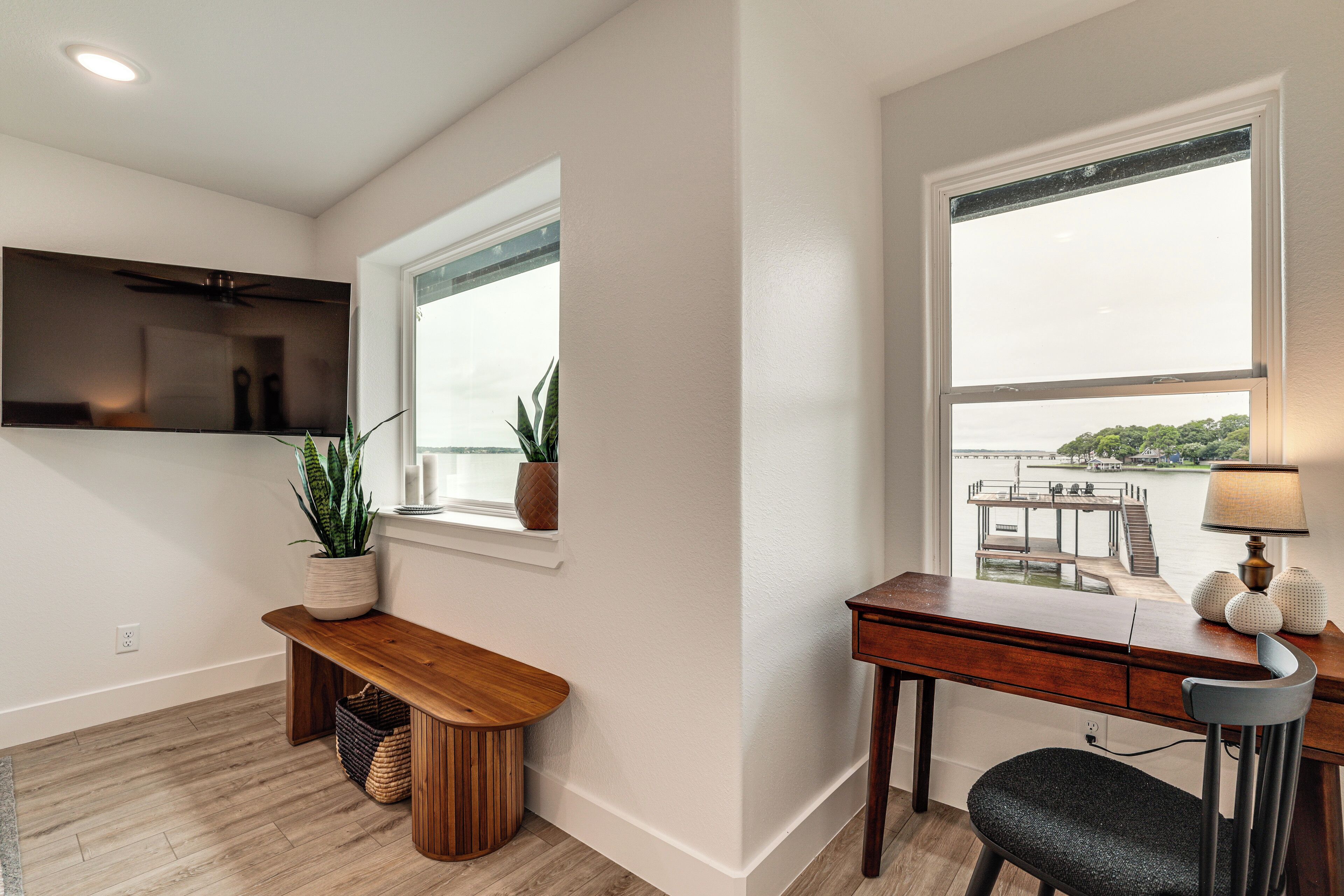 A modern room with a desk, chair, bench, and potted plants.