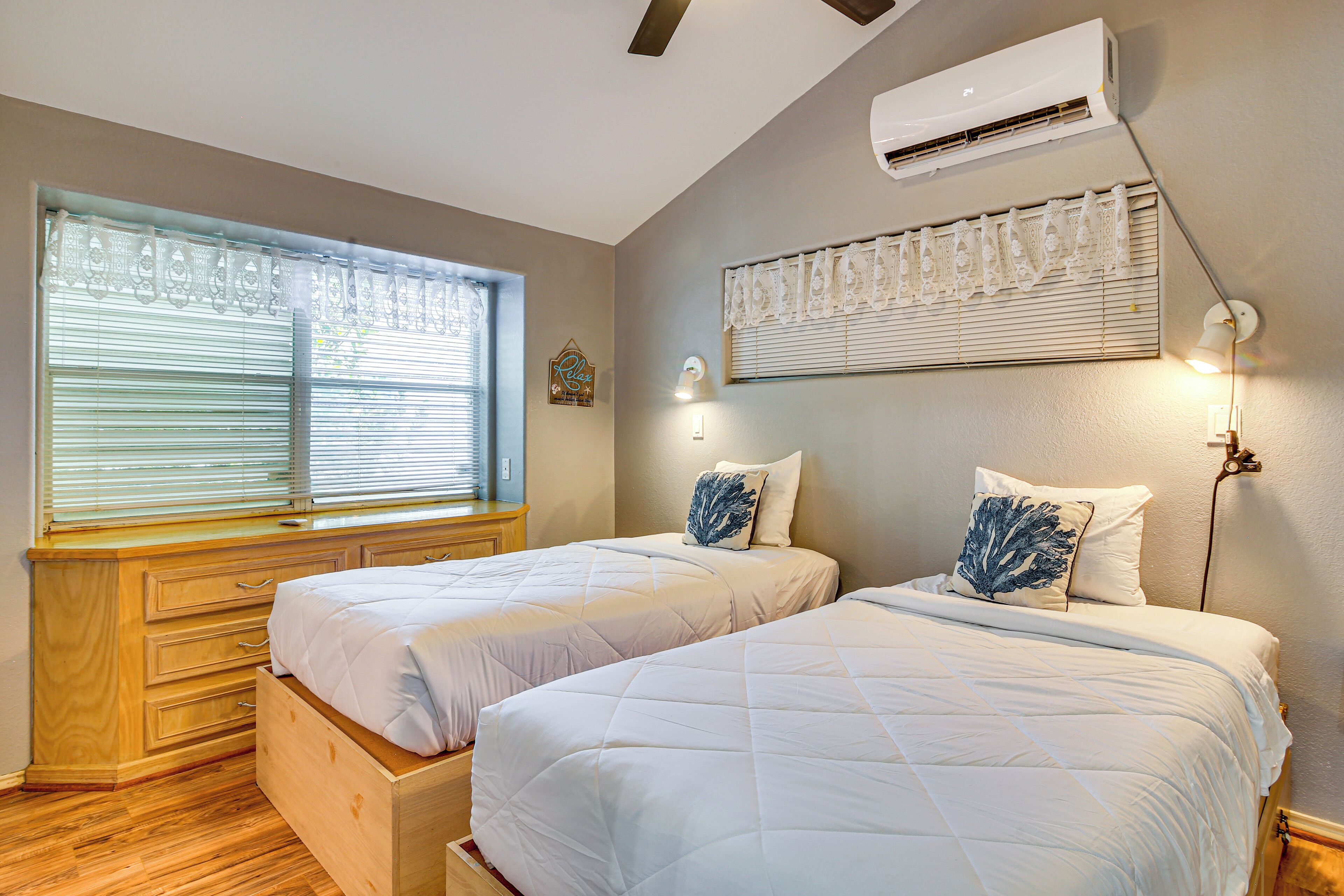 Un dormitorio con dos camas, un aparador de madera y una ventana con persianas.