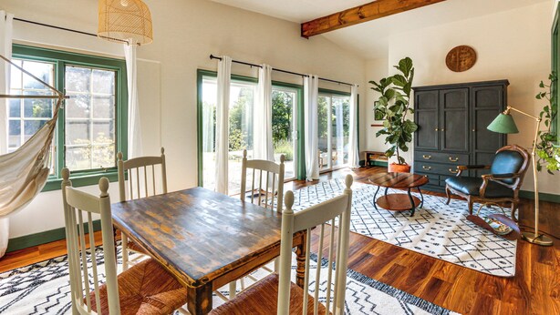 A dining area with a wooden table and chairs, a hammock, and a dark cabinet with drawers. - Walkable Location: Historic Home in Charles Town! (Charles Town)