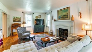 A living room with a fireplace, a sofa, a chair, a coffee table, and a rug. - Walkable Location: Historic Home in Charles Town! (Charles Town)