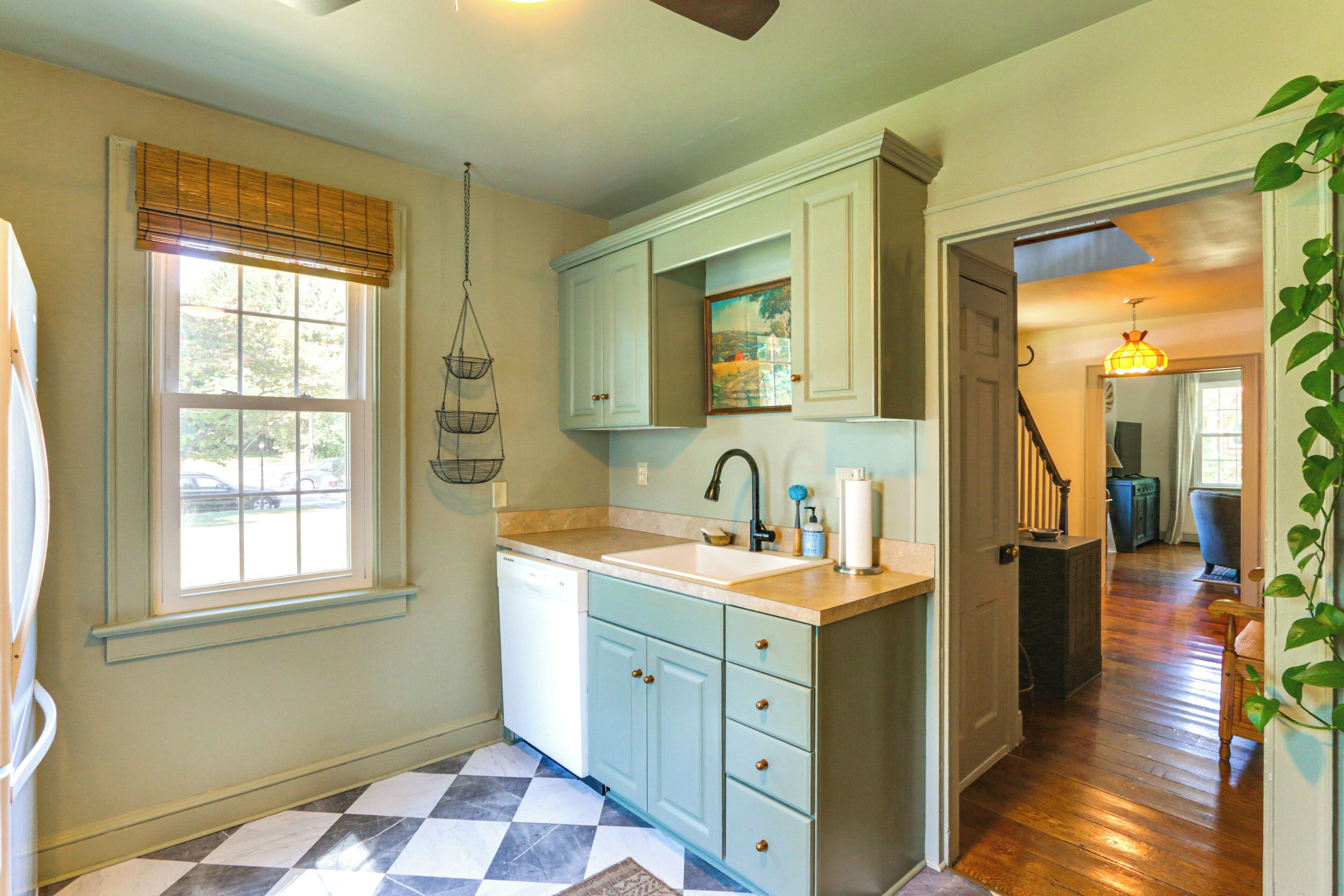 A kitchen with light blue cabinets, a white dishwasher, and a checkered floor.