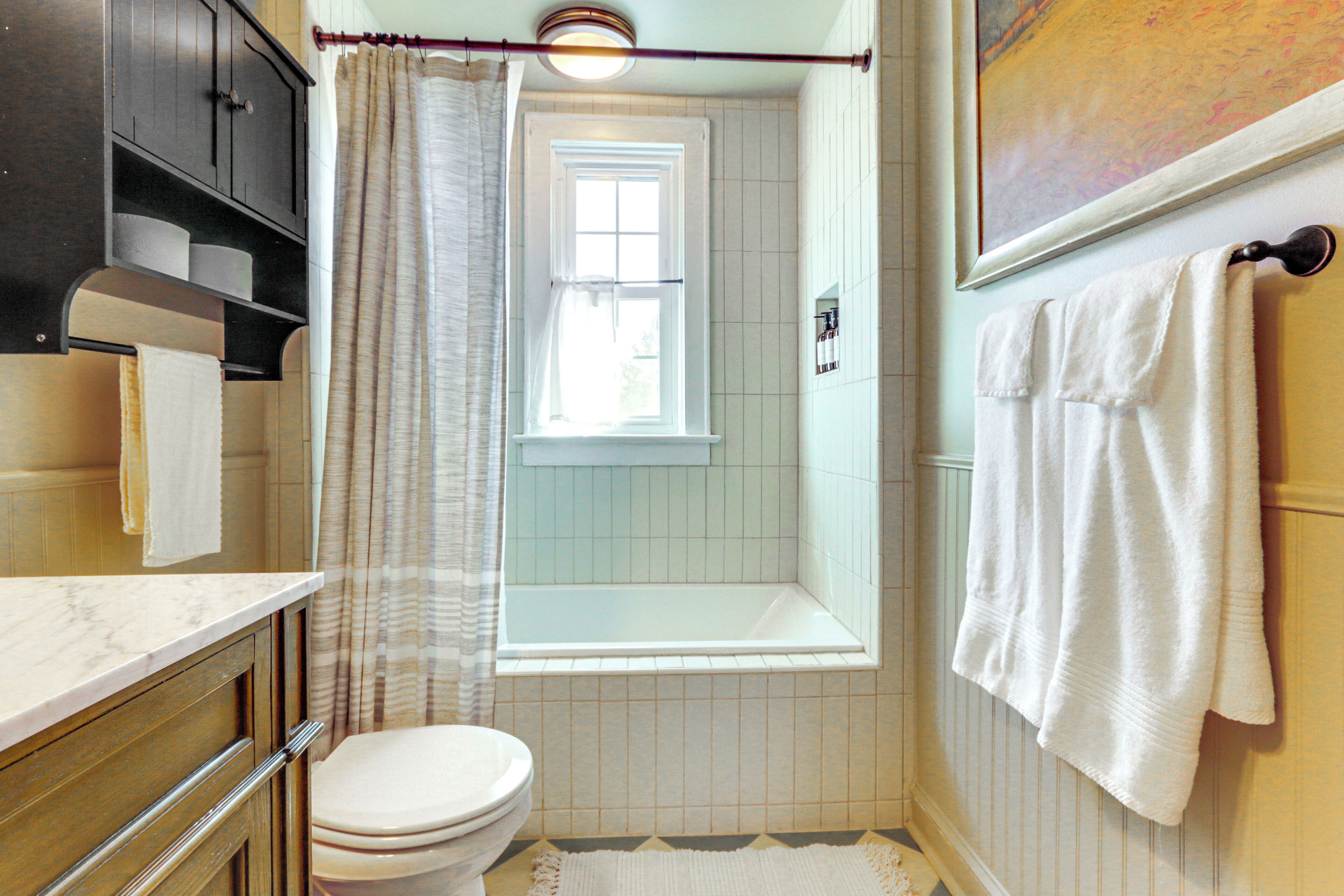 Une salle de bain équipée de toilettes, d’une baignoire, d’un rideau de douche et d’un porte-serviettes.