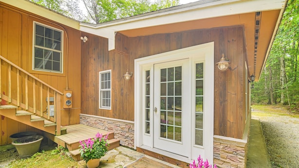 A wooden house with a front porch, stone steps, and a door with glass panels. - Walk to Water: Outdoor Gem w/ Bunkhouse in Madison (Madison)