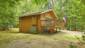 A wooden cabin with a balcony, an American flag, and a small shed. - Walk to Water: Outdoor Gem w/ Bunkhouse in Madison (Madison)