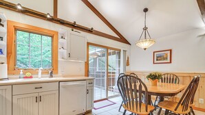A kitchen with white cabinets, a wooden dining table with chairs, and a hanging light fixture. - Walk to Water: Outdoor Gem w/ Bunkhouse in Madison (Madison)