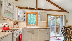 A kitchen with white cabinets, a red kettle, and a window overlooking greenery. - Walk to Water: Outdoor Gem w/ Bunkhouse in Madison (Madison)