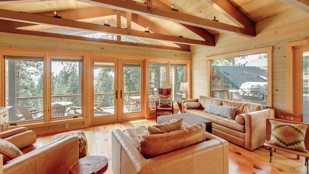Un salón amplio con vigas de madera, ventanas grandes y muebles de cuero.