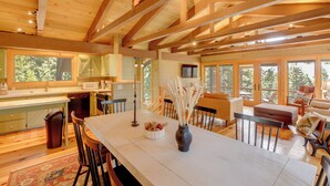 Una cocina amplia con vigas de madera, un comedor con una mesa larga y una zona de estar acogedora con vistas al exterior.