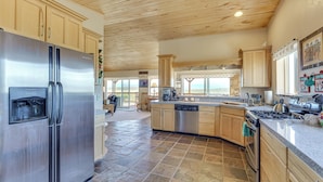 A spacious kitchen with a stainless steel refrigerator, wooden cabinets, a dishwasher, and a large island with a stove. - Walk to Lake: Scenic Southern Colorado Escape! (San Luis)