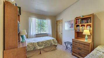 A bedroom with a bed, a dresser, a bookshelf, a window with curtains, and a door.