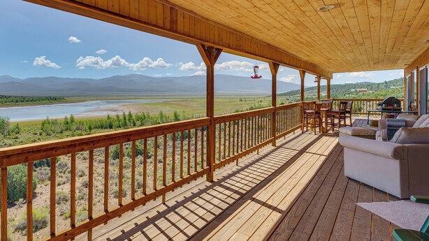 A wooden deck with a view of a river and mountains. - Walk to Lake: Scenic Southern Colorado Escape! (San Luis)