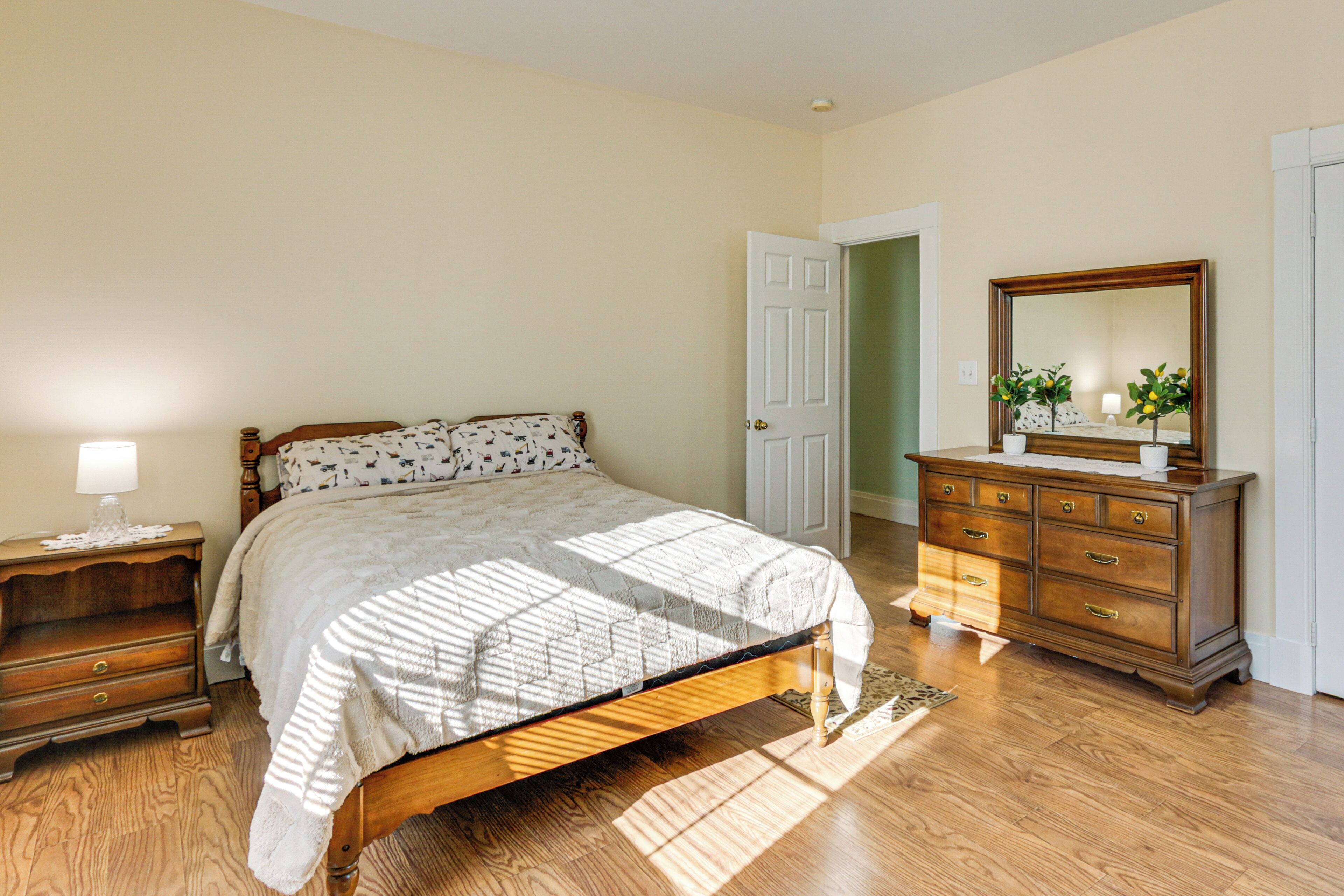 Une chambre à coucher avec un lit en bois, une table de chevet, une commode et un miroir.