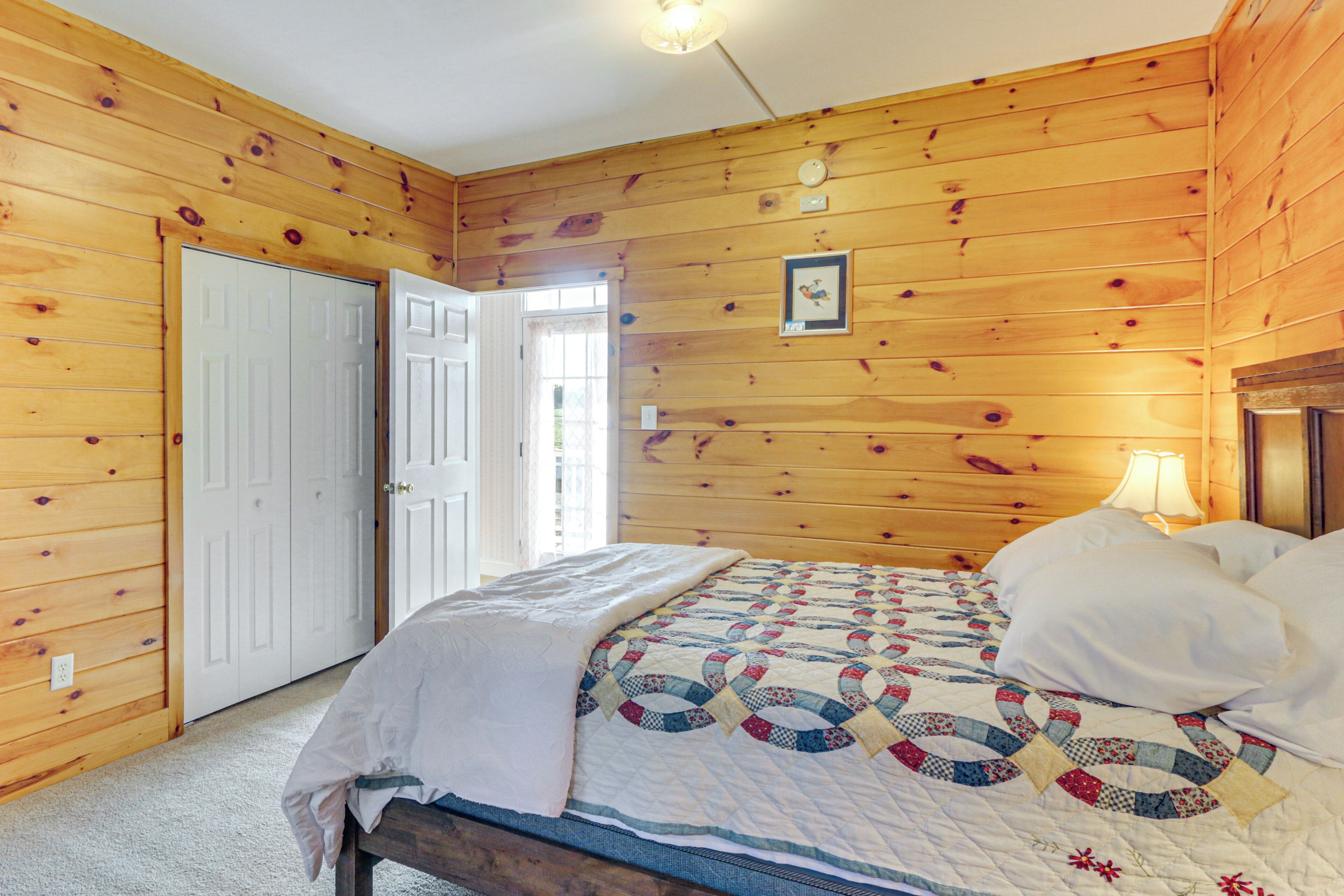 A wooden-paneled bedroom with a bed, a door, and a window.