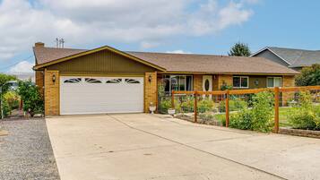 A two-story house with a garage, a fenced garden, and a clear sky.