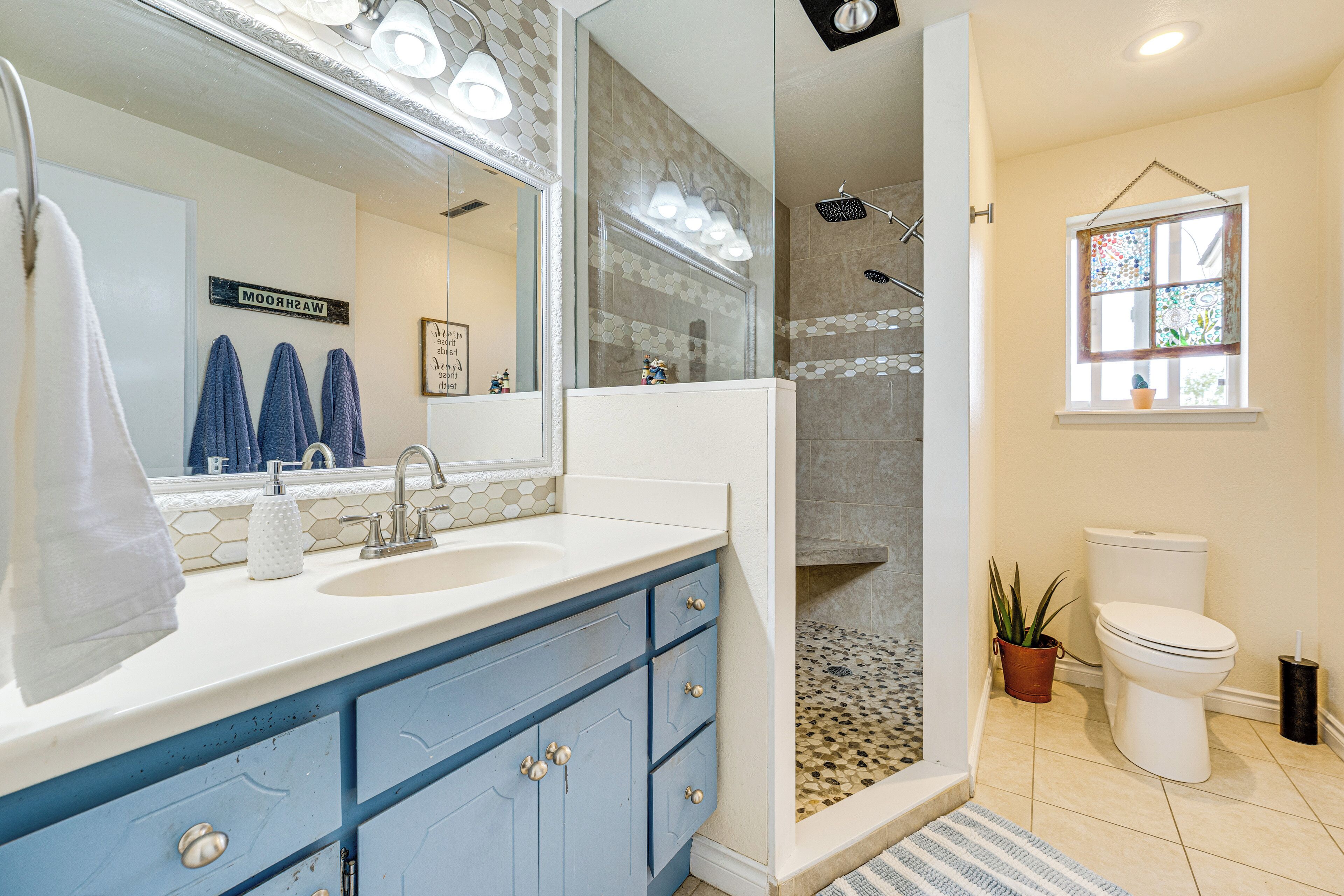 A bathroom with a large mirror, a shower, a toilet, and a sink with a towel rack.