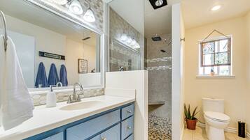 A bathroom with a large mirror, a shower, a toilet, and a sink with a towel rack.