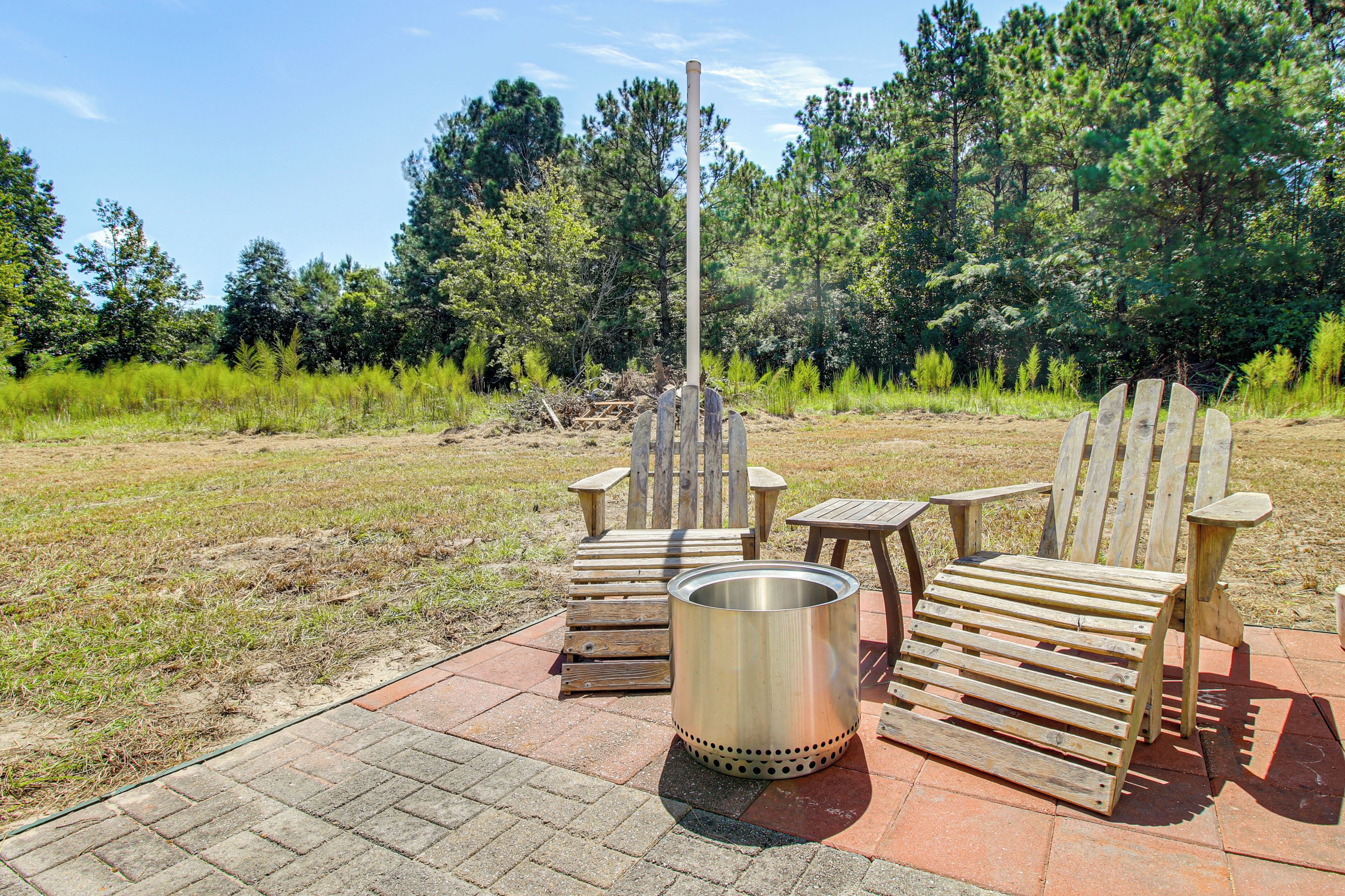 Eine Holzterrasse mit Adirondack-Stühlen und einem Metallgrill.