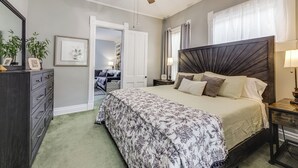 Ein Schlafzimmer mit Bett, Kommode, Nachttisch und Deckenventilator.