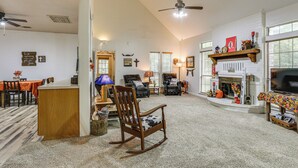 A spacious living room with a fireplace, a dining area, and a kitchen. - Relax By the Lake: Quiet East Texas Retreat (Village Mills)