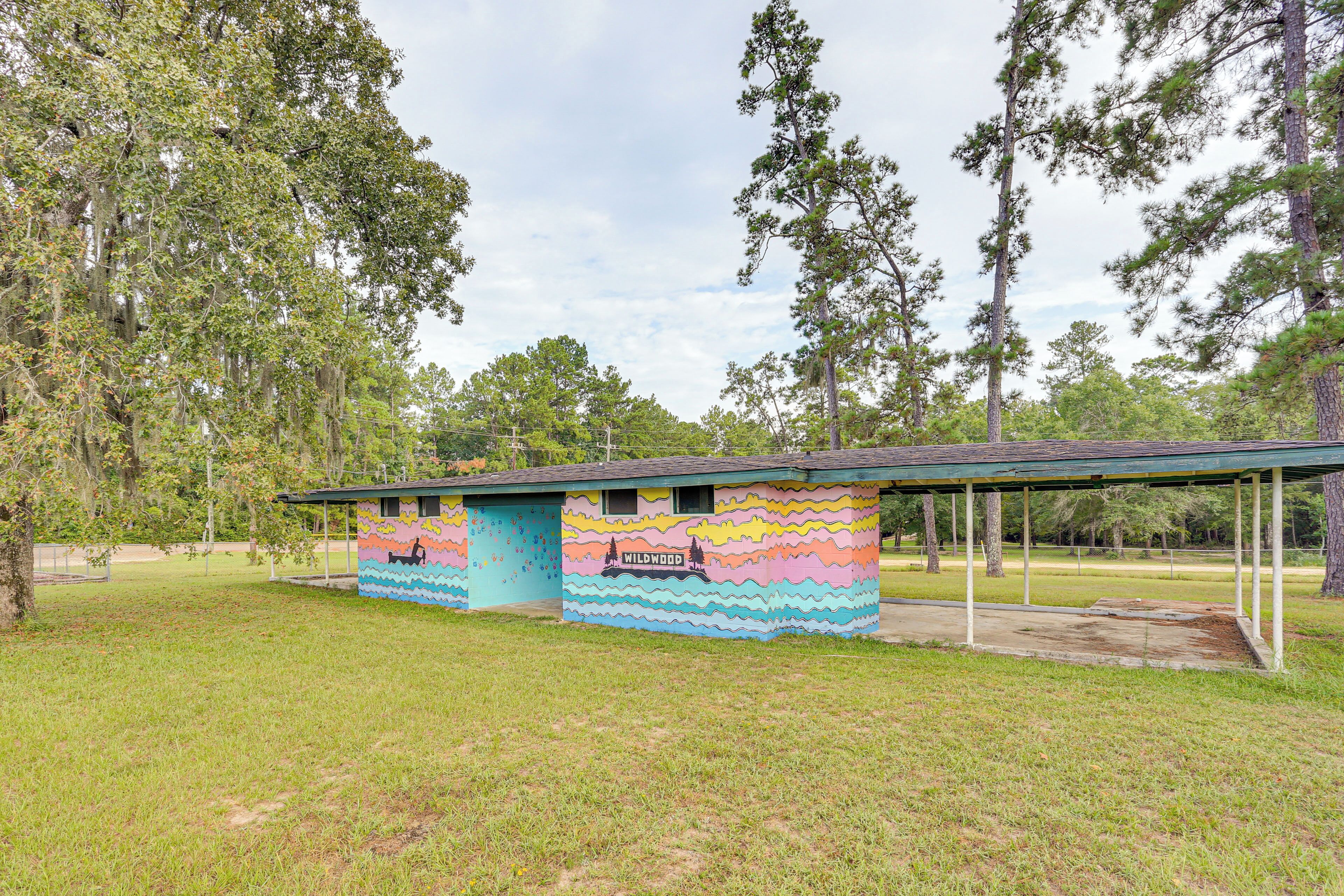 A small, colorful building with a mural, surrounded by trees.