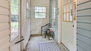 A narrow hallway with a chair and a small table, a patterned rug, and a door with a window. - Relax By the Lake: Quiet East Texas Retreat (Village Mills)