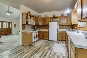 Eine Küche mit Holzausstattung, einem weißen Kühlschrank, einer Mikrowelle und einer Kaffeemaschine.