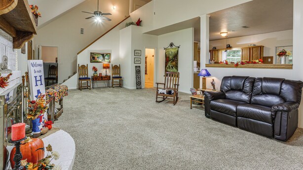 A spacious living room with a leather sofa, a wooden rocking chair, and a staircase leading to an upper level. - Relax By the Lake: Quiet East Texas Retreat (Village Mills)