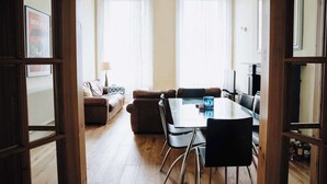 Un salon avec un canapé, une table à manger et des chaises, ainsi qu’un lustre.