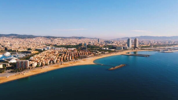 Vista aérea de una ciudad costera con playa, edificios y cielo despejado.