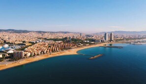 Une vue aérienne d’une ville côtière, avec une plage, des bâtiments et un ciel dégagé.
