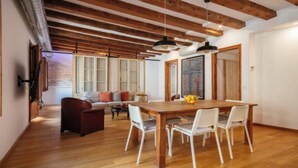 Un área de comedor con una mesa y sillas de madera, un sofá y un cuadro en la pared.