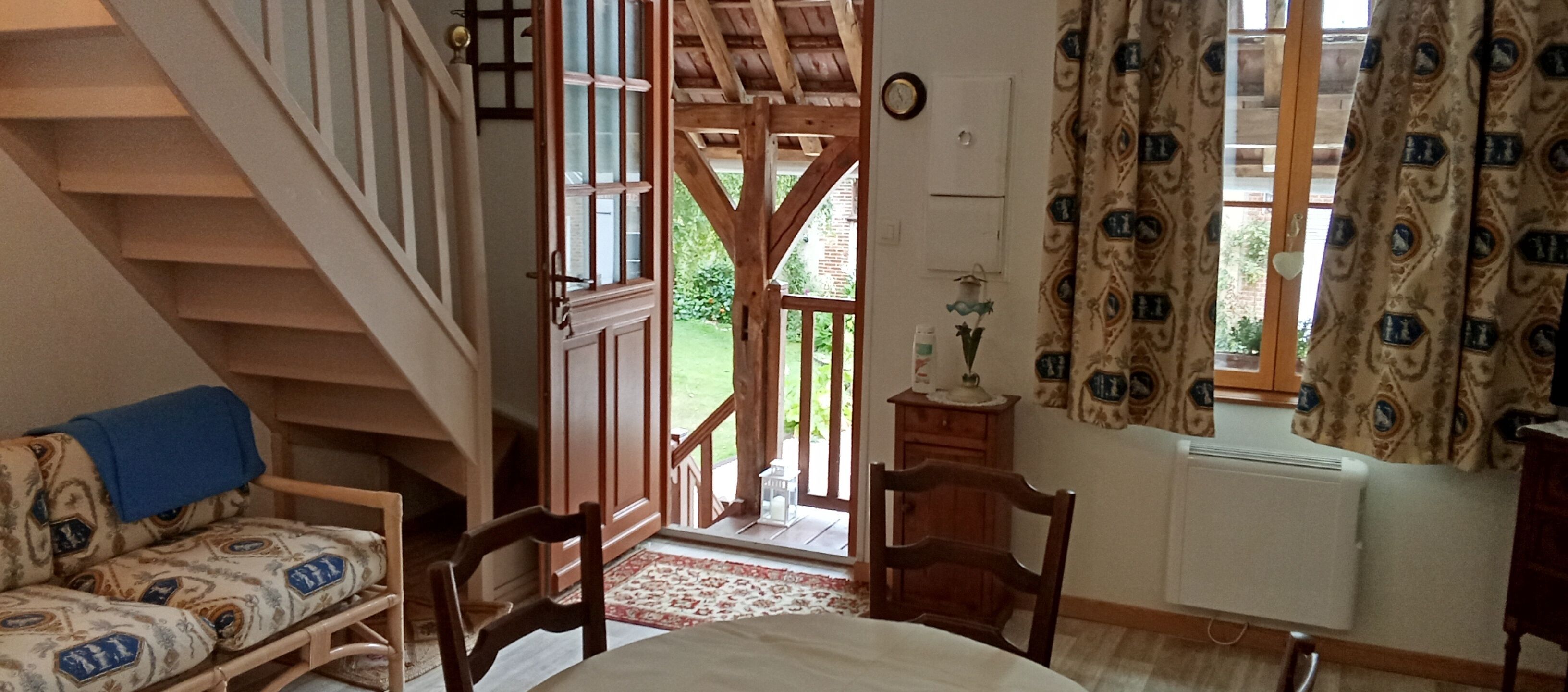 Une pièce avec un escalier, un lit, une chaise, une petite table et une fenêtre avec des rideaux.