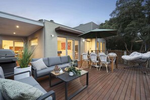 A modern outdoor patio with a sofa, dining table, and chairs. - Ebb & Flow (Blairgowrie)