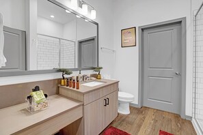 Ein modernes Badezimmer mit einem Holzlagerflächen, einem großen Spiegel und einer weißen Toilette.