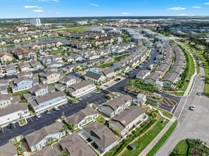 Ein Wohngebiet mit Häusern, die an einer gewundenen Straße in Reih und Glied angeordnet sind, ein Gewässer und ein weit entfernter Blick auf ein großes Gebäude.