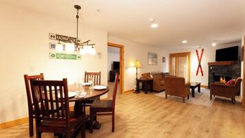 A dining area with a wooden table and chairs, a fireplace, and a television in the living room.