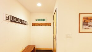 Een hal met een houten bankje, een bord waarop staat 'UNLOAD HERE', een bord met 'SNAKEDANCE 409' en een ingelijst beeld aan de muur.