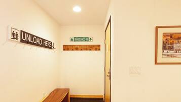 A hallway with a wooden bench, a sign reading "UNLOAD HERE", a "SNAKEDANCE 409" sign, and a framed picture on the wall.