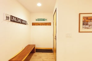 A hallway with a wooden bench, a sign reading "UNLOAD HERE", a "SNAKEDANCE 409" sign, and a framed picture on the wall. - Lift 1 Lookout - Snakedance Condos - WiFi - Ski Locker - Shops - Restaurants (Taos Ski Valley)