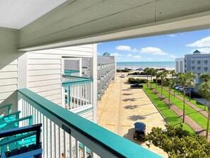 A hotel with a balcony, a parking lot, and a view of the beach.